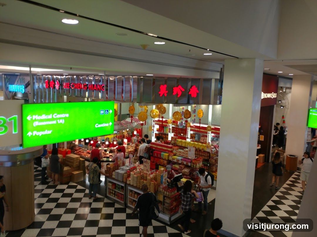 Interior of a busy shopping mall with various stores and directional signage.