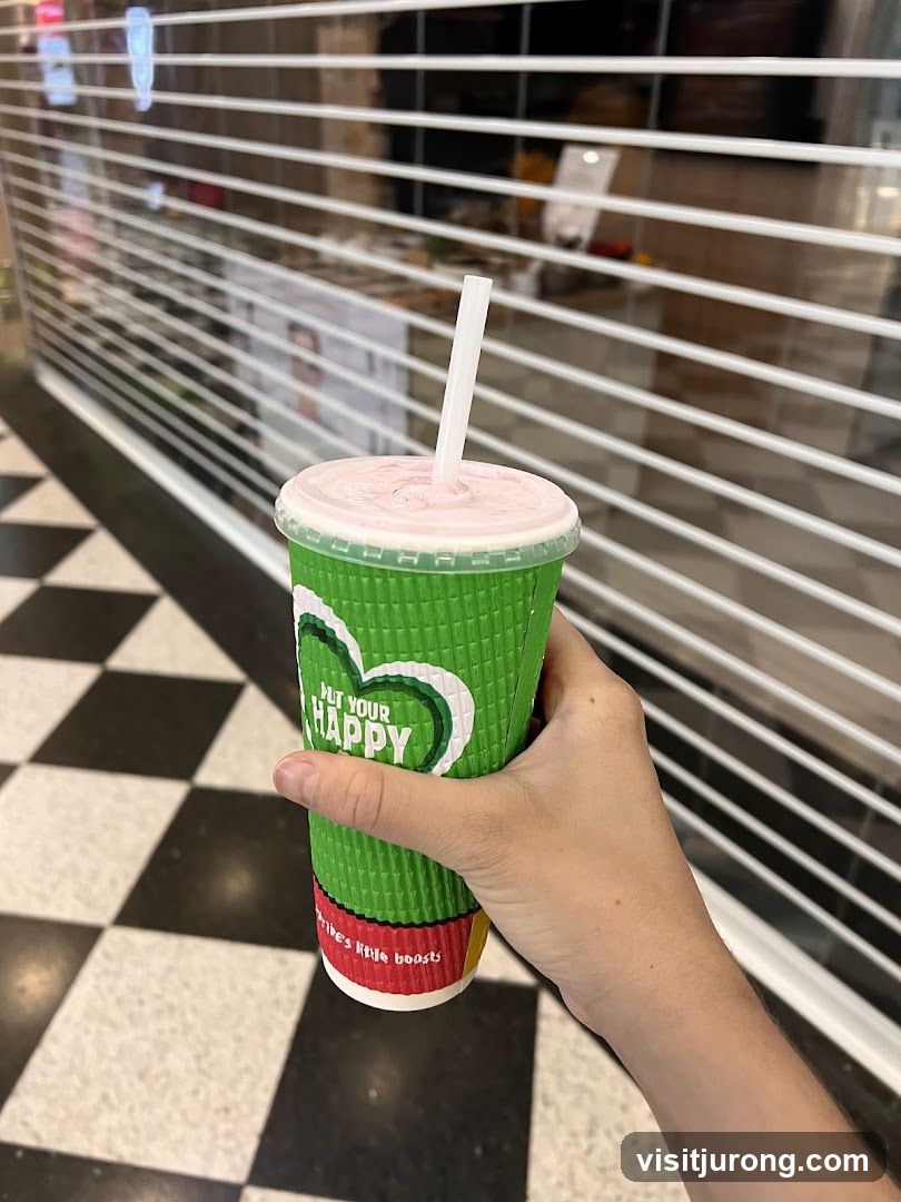 Green cup with a pink drink and straw