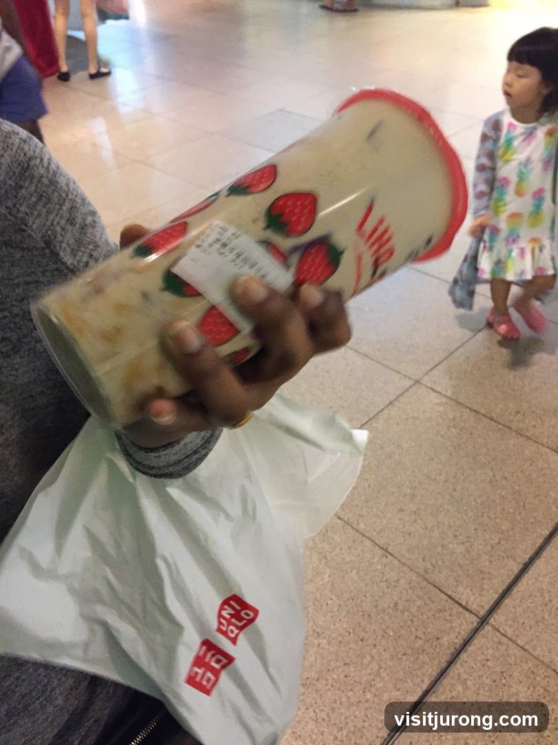 Person holding a large beverage cup with strawberries