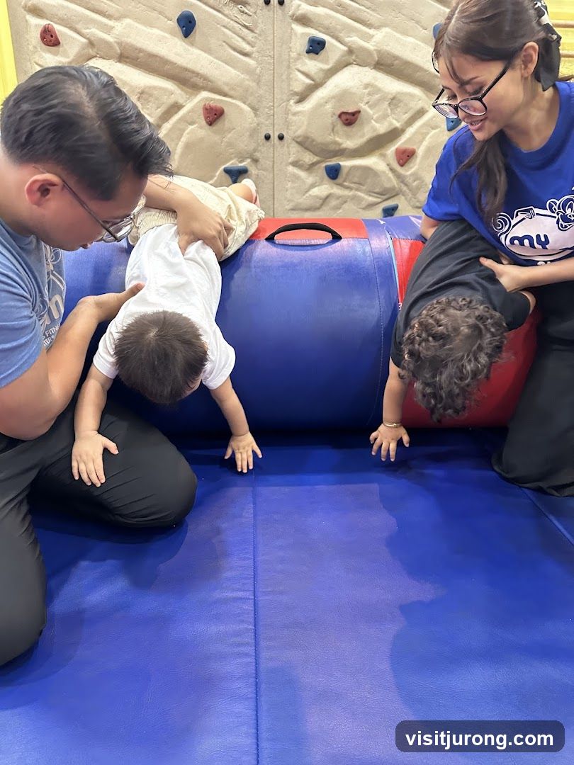 Children and adults playing on a soft cylinder and climbing wall