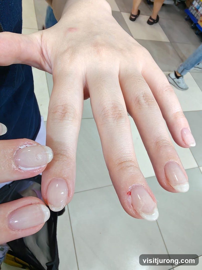Close-up of a hand with partially done French manicured nails