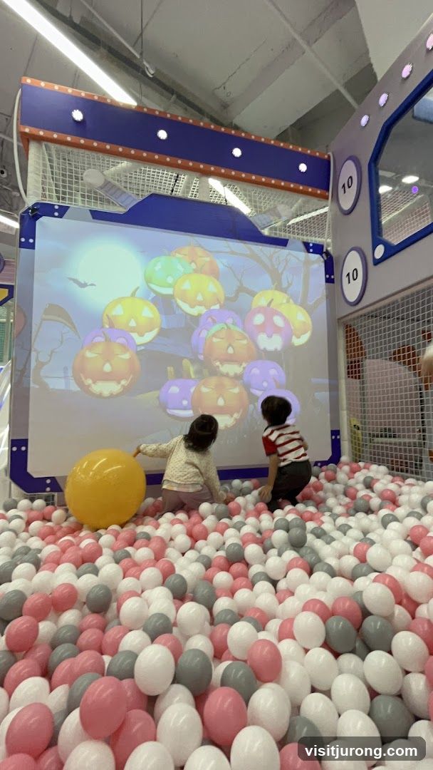 Children playing in a ball pit with a projected Halloween game