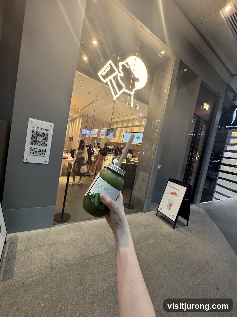 Person holding a green drink outside a shop