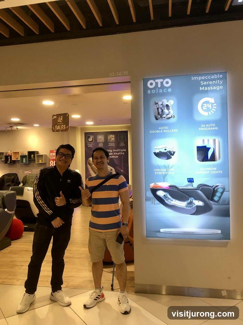 Two men posing in front of a massage chair advertisement