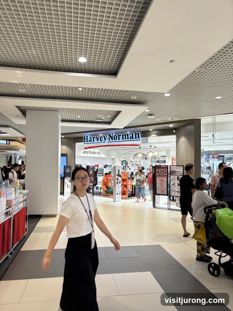 People walking in a mall with a Harvey Norman store in the background