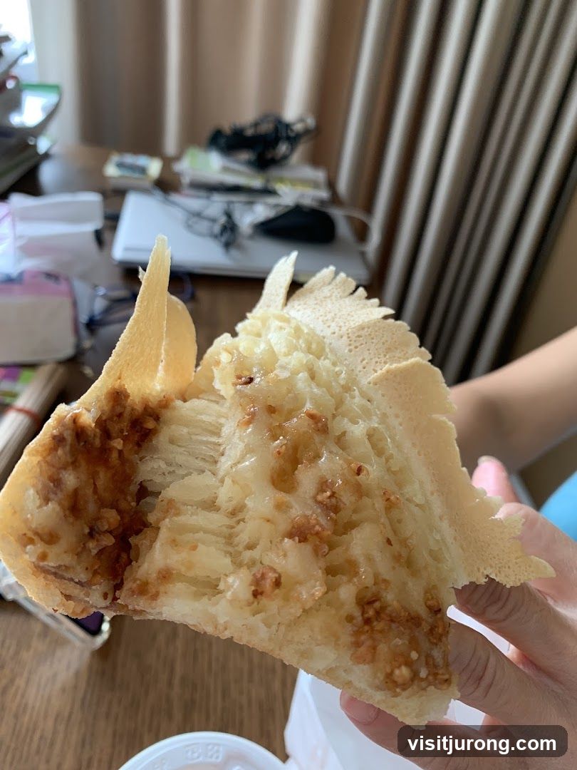 Close-up of a sweet pastry with a crunchy exterior and a soft, layered interior filled with nuts and syrup.