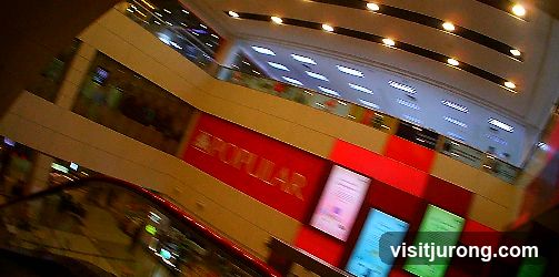 Interior of a shopping mall with a large red sign that says POPULAR.