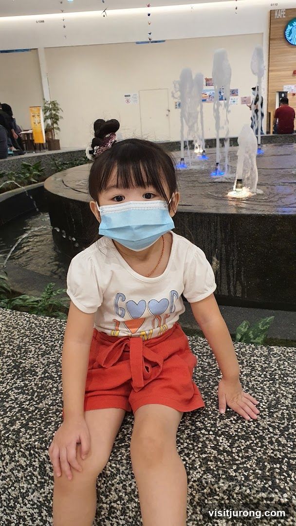 Young girl in a mask by a fountain