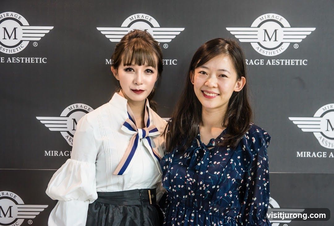 Two women posing in front of a branded backdrop