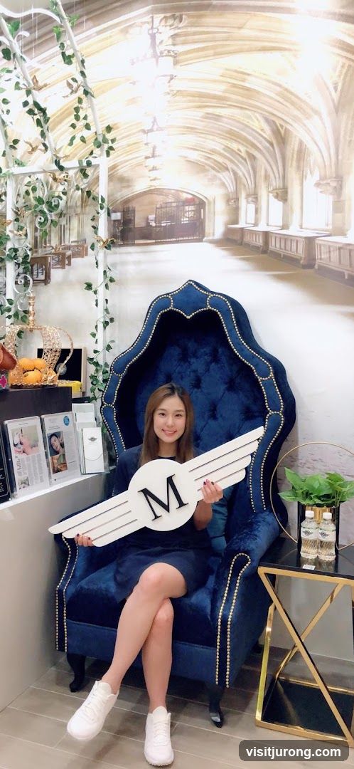 Woman holding a winged letter M sign