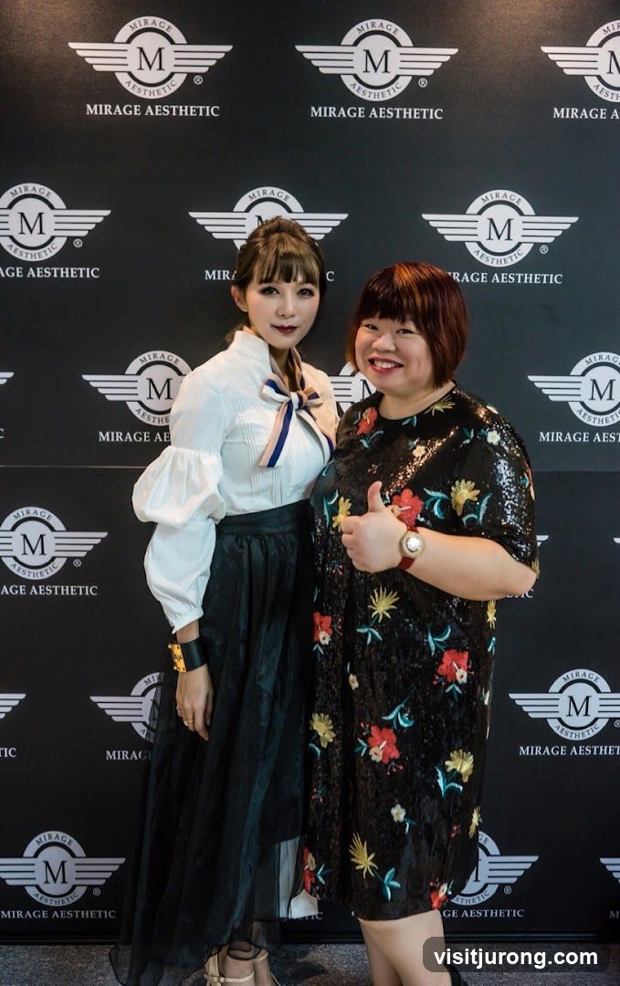 Two women posing in front of a branded backdrop