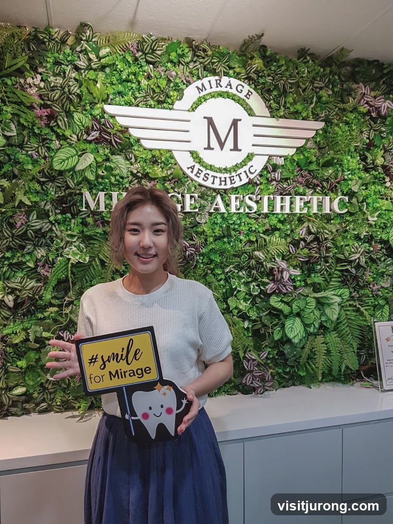 Woman holding a sign in front of a green wall with a logo