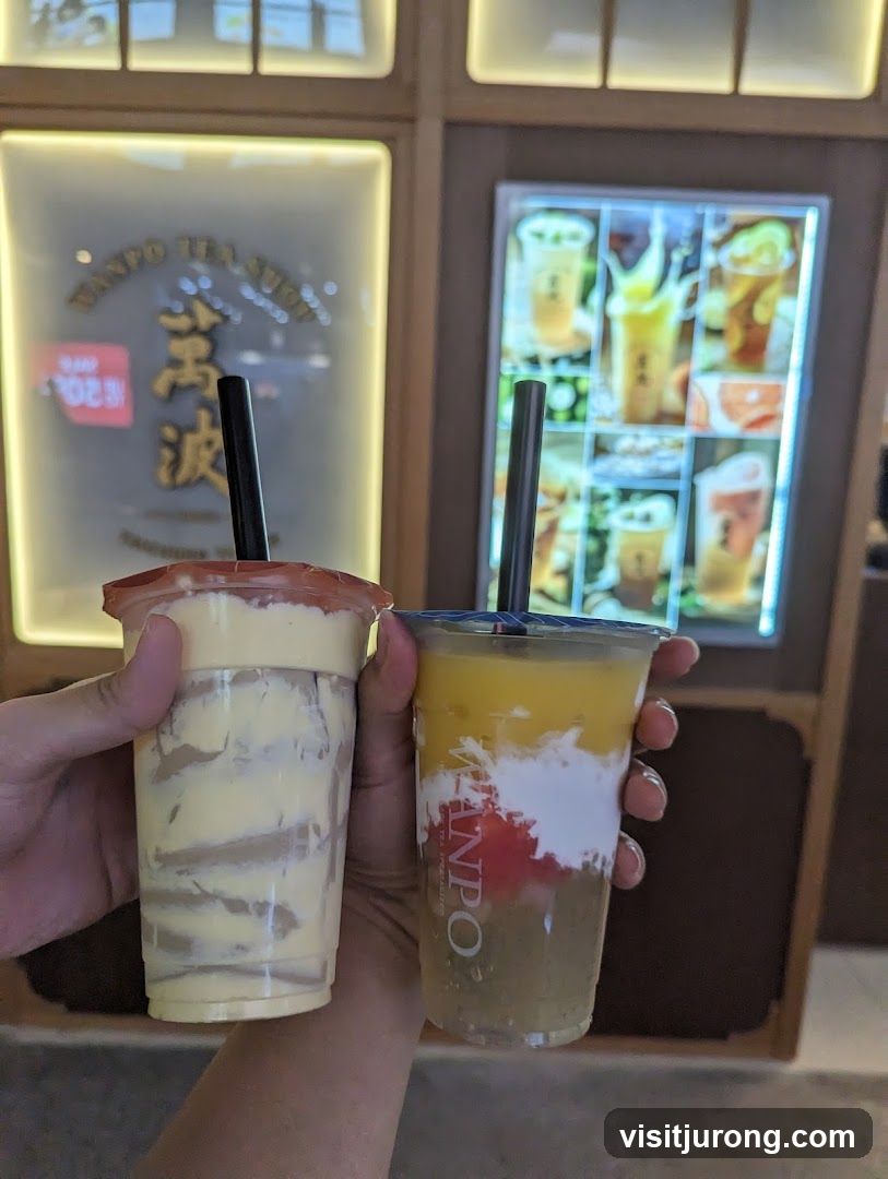 Two layered drinks held in front of a tea shop display