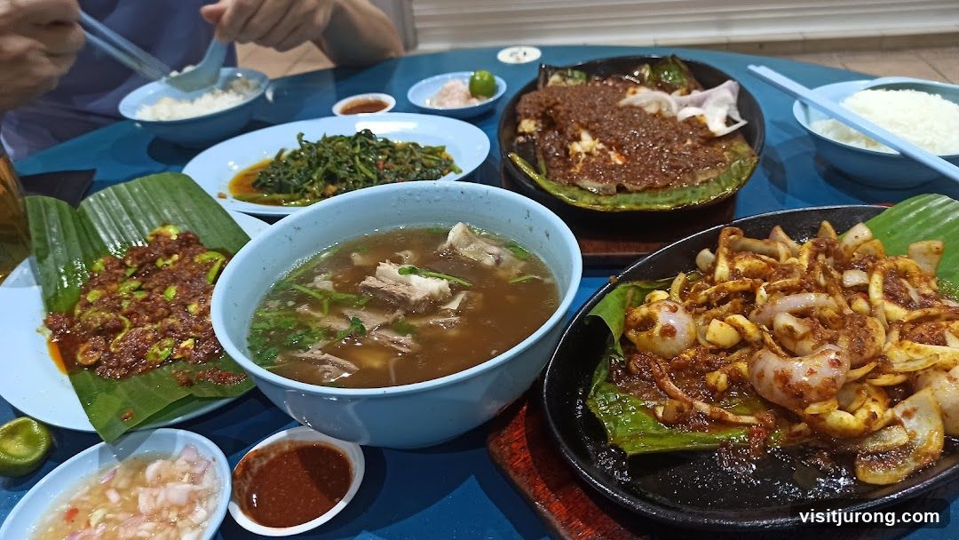A table laden with various dishes, including soup, stir-fried vegetables, and seafood.