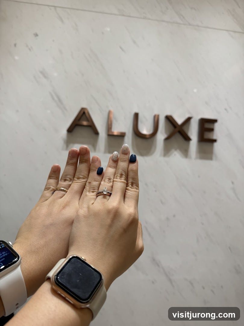 Hands with rings and watches in front of a wall with "ALUXE" lettering