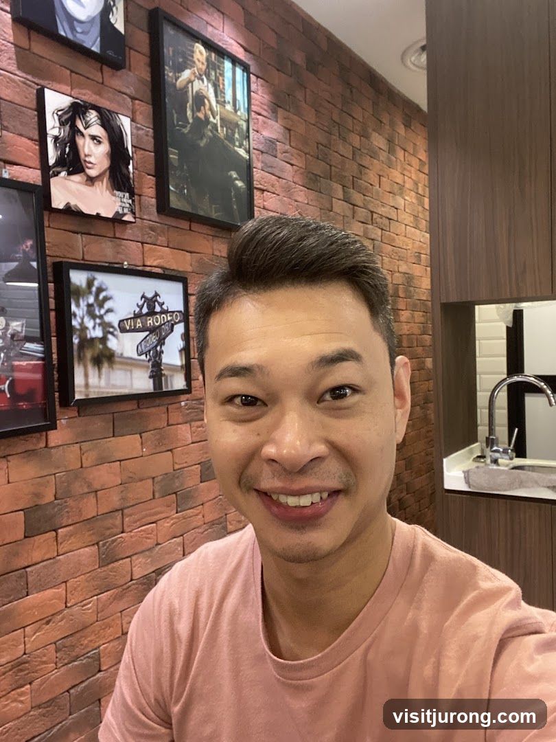 Man smiling in front of brick wall with framed pictures