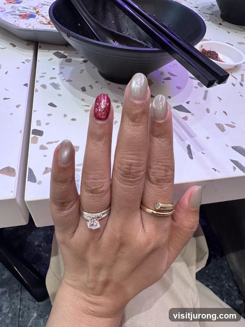 Close-up of a hand with manicured nails and rings on a table with food remnants.