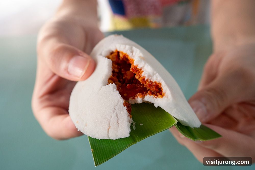 Close-up of a person holding a white steamed bun with a spicy filling