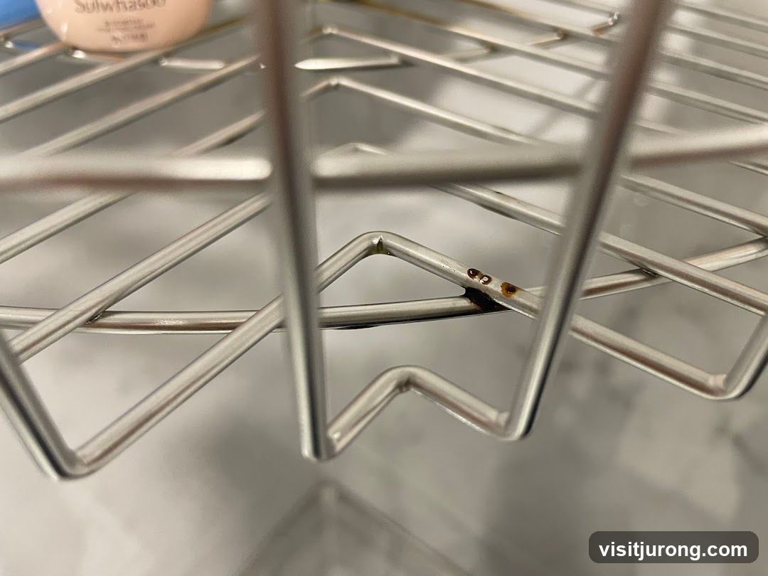 Close-up of a metal shelf with small brown spots.