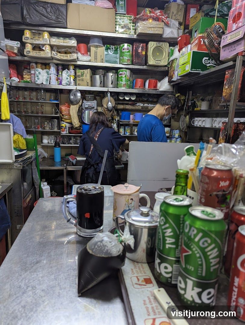 Inside a small shop with shelves stocked with goods and two people working.
