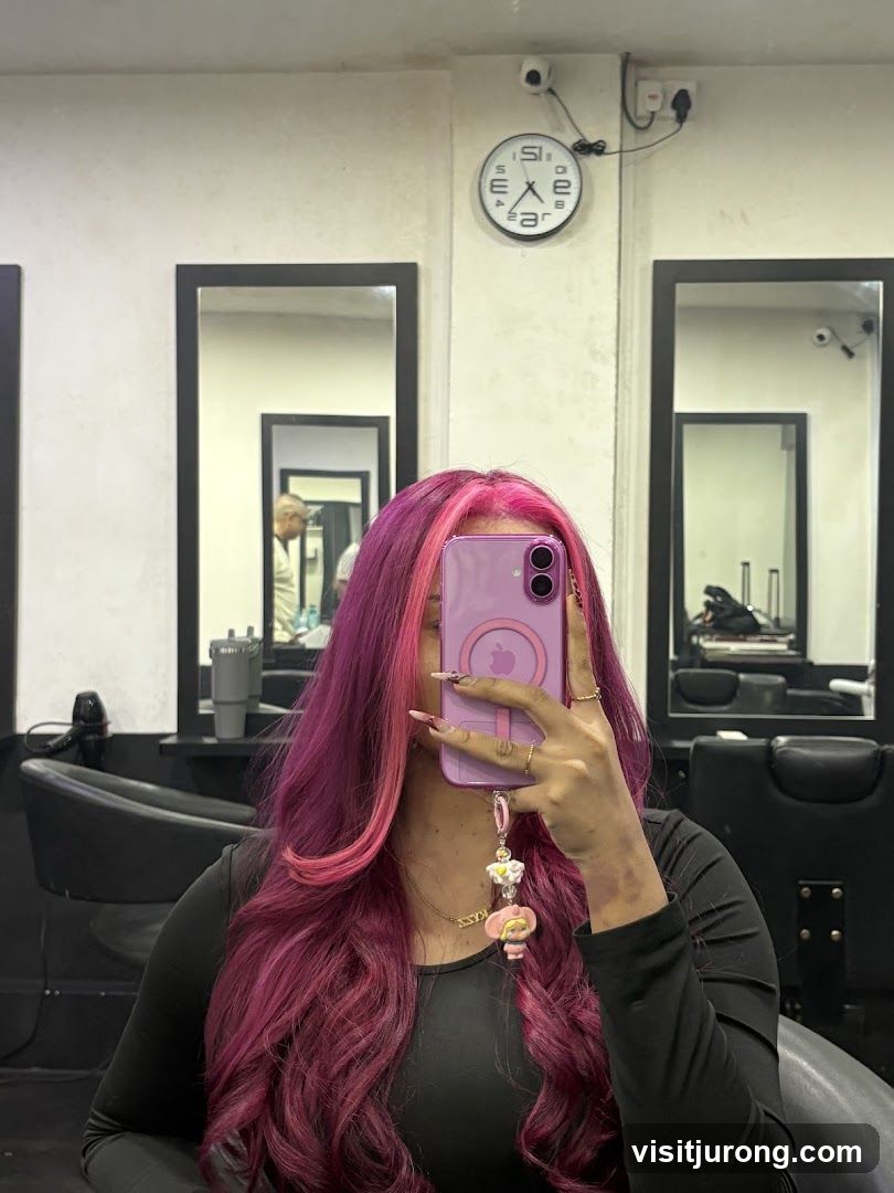 Woman with pink and purple hair taking a selfie in a salon