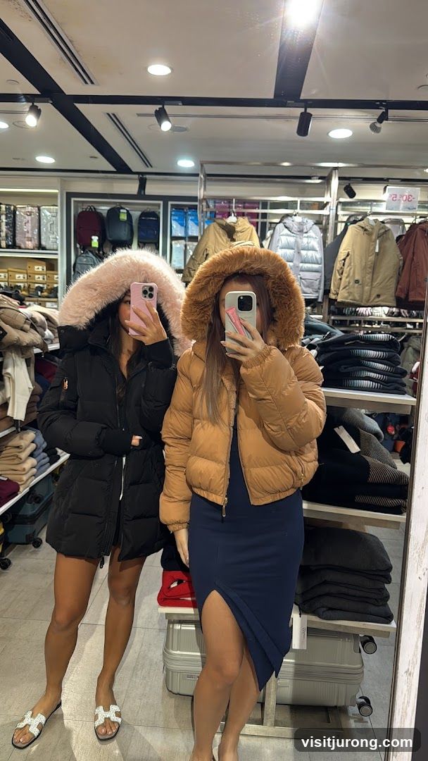 Two women in puffer jackets taking a mirror selfie