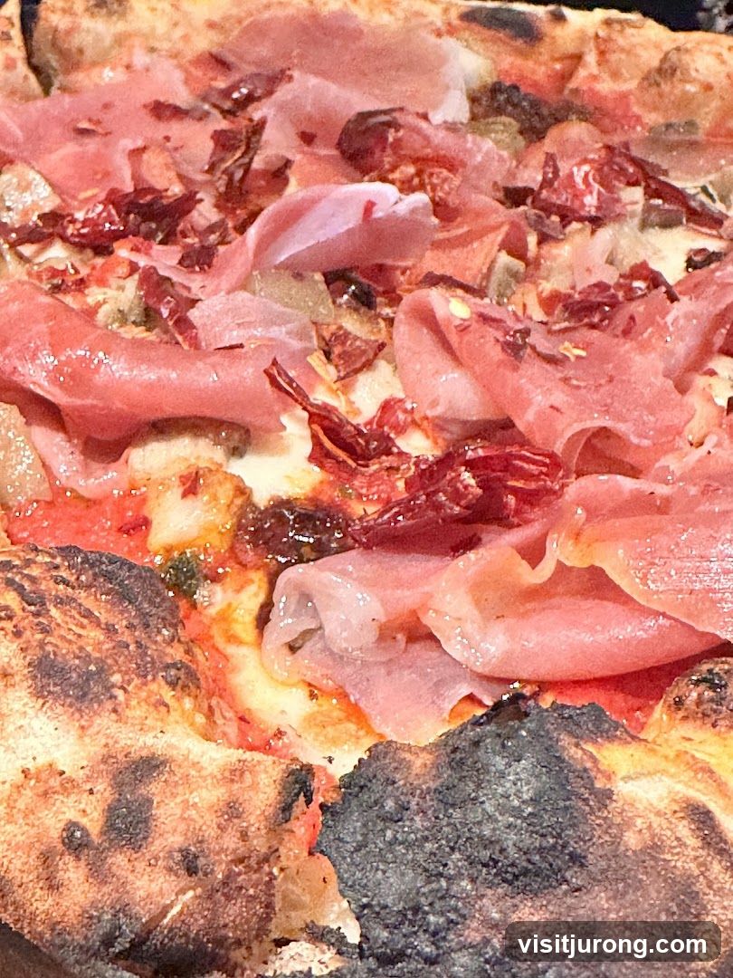 Close-up of a pizza with prosciutto and chili flakes