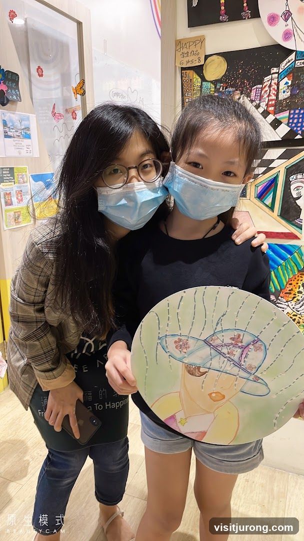 Two people wearing masks holding artwork