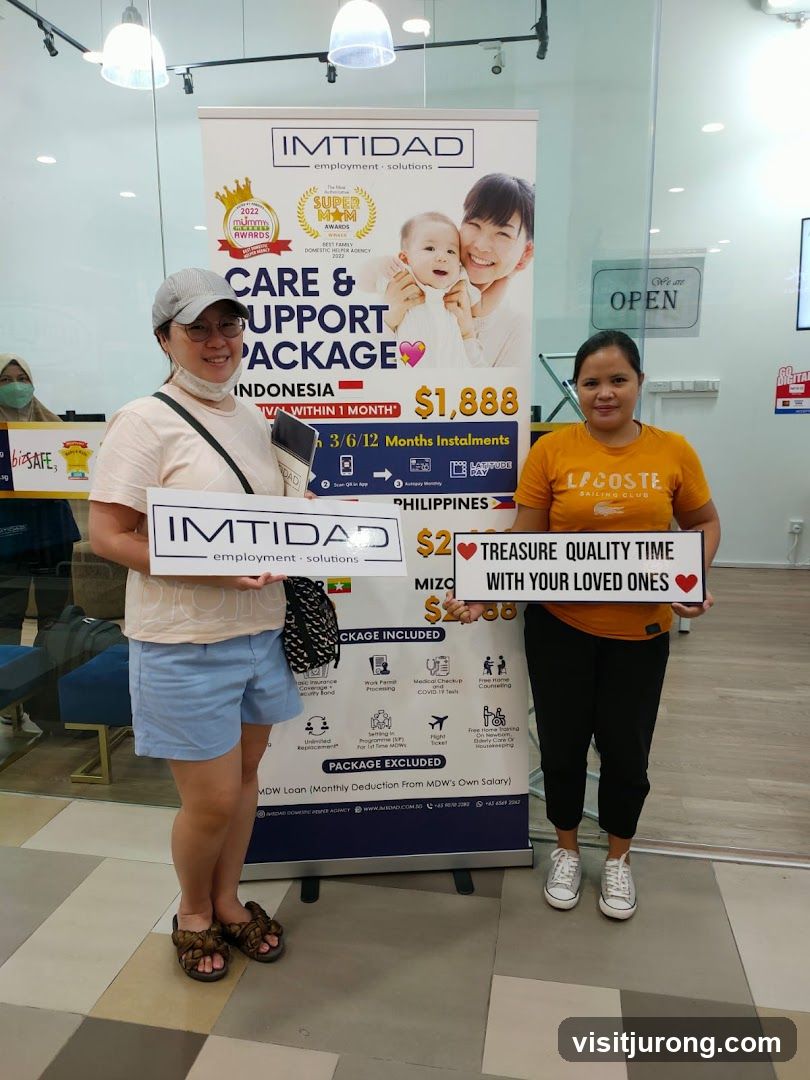 Two women holding signs in front of a promotional banner