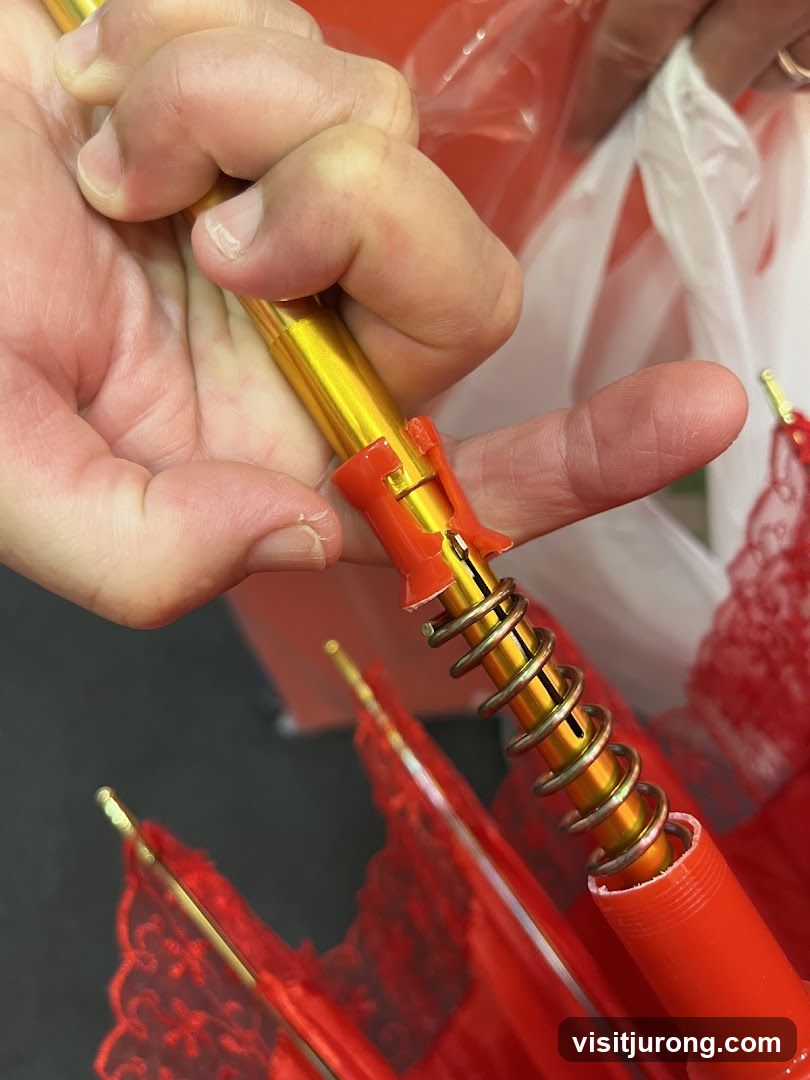 Close-up of a person's hands operating a red umbrella mechanism
