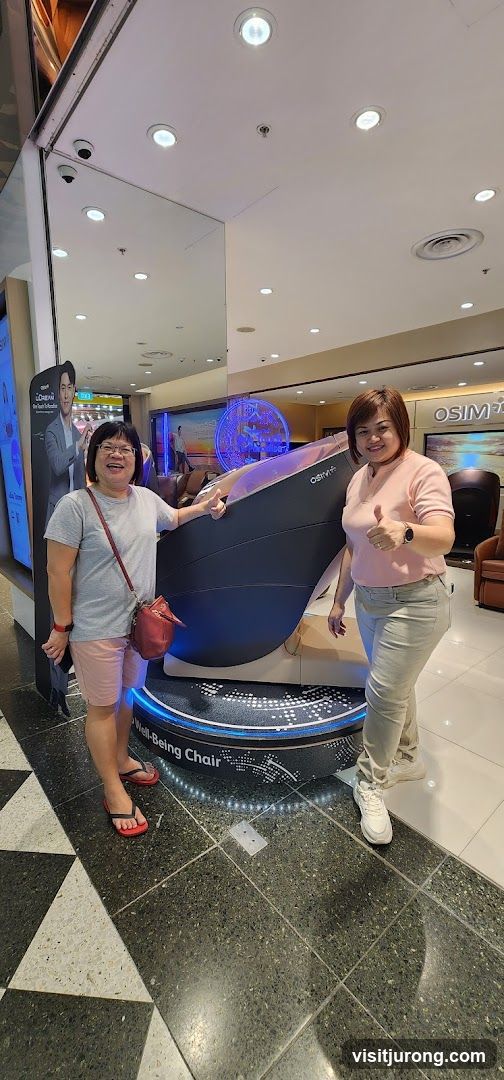 Two women posing with a massage chair