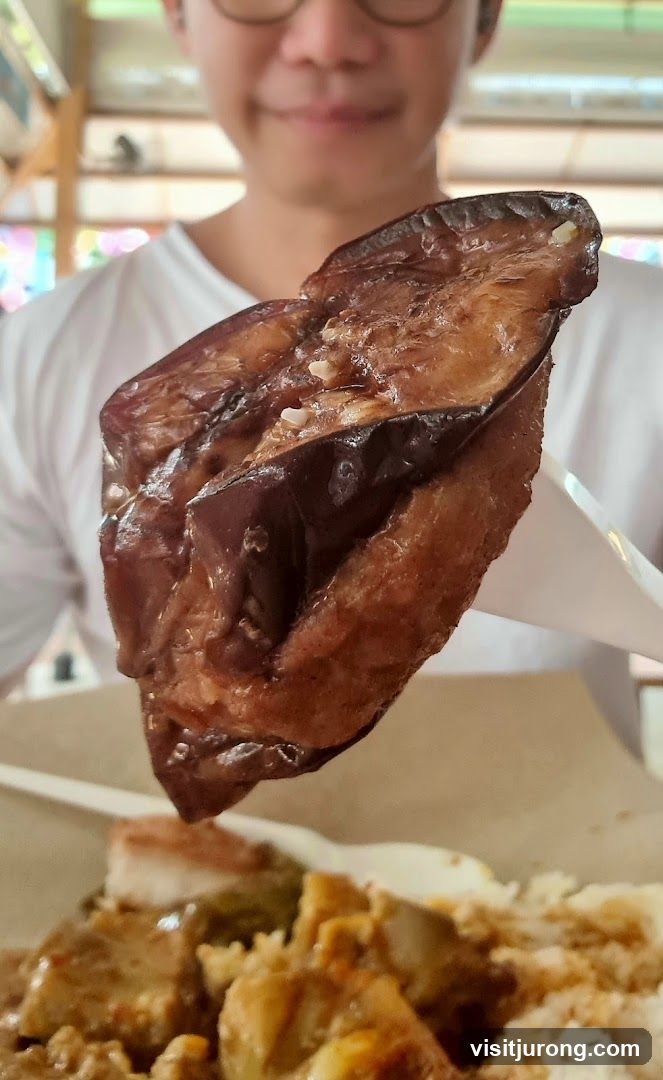 Person holding cooked eggplant over a meal