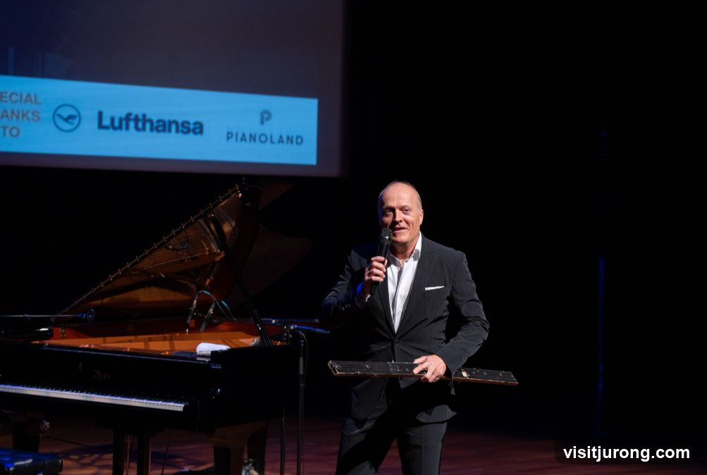 Man speaking on stage with piano