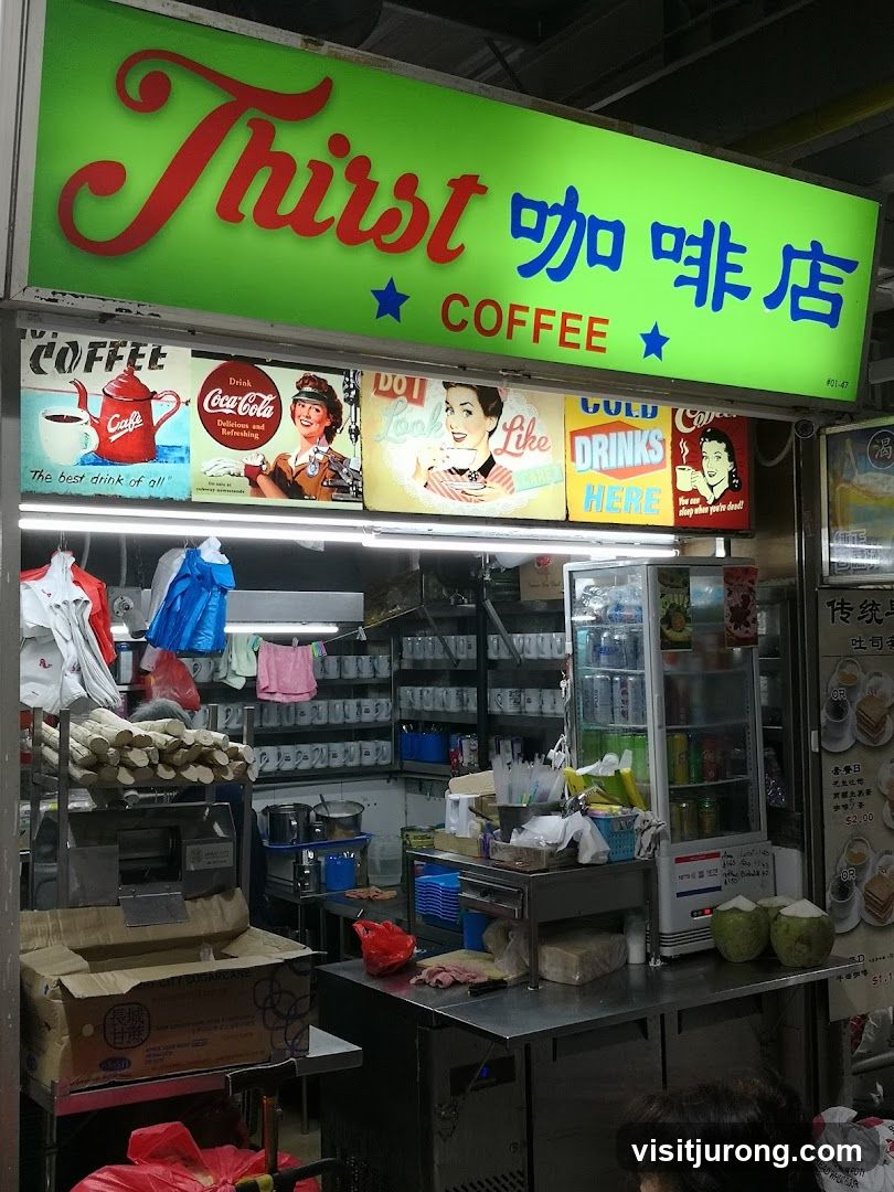 A brightly lit green sign with red and blue lettering reads "Thirst 咖啡店 COFFEE". Below the sign are several vintage-style advertisements for coffee and Coca-Cola. The storefront itself is visible, showing a counter with various items, including coconuts, a refrigerator stocked with drinks, and stacks of cups. There is also a sugarcane juicing machine.