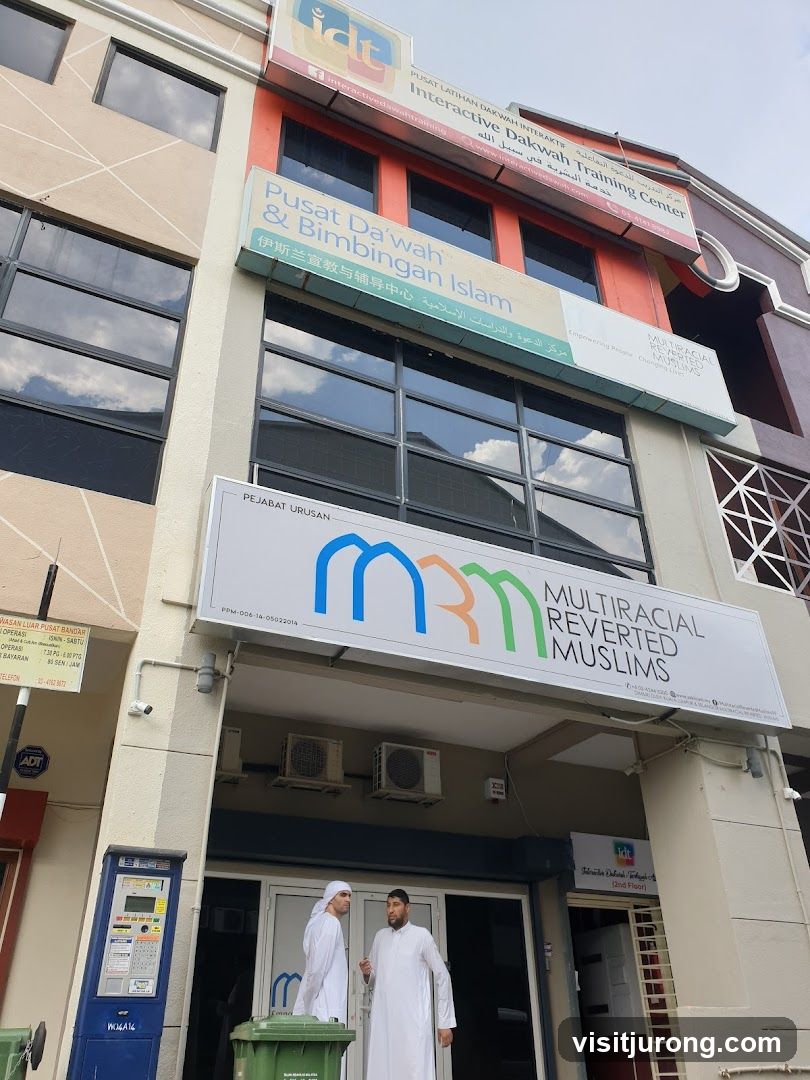 The exterior of a building with multiple signs for Islamic training and outreach centers. The main sign reads "MULTIRACIAL REVERTED MUSLIMS" with a logo. Below this, the entrance to the building is visible with two men standing at the doorway.