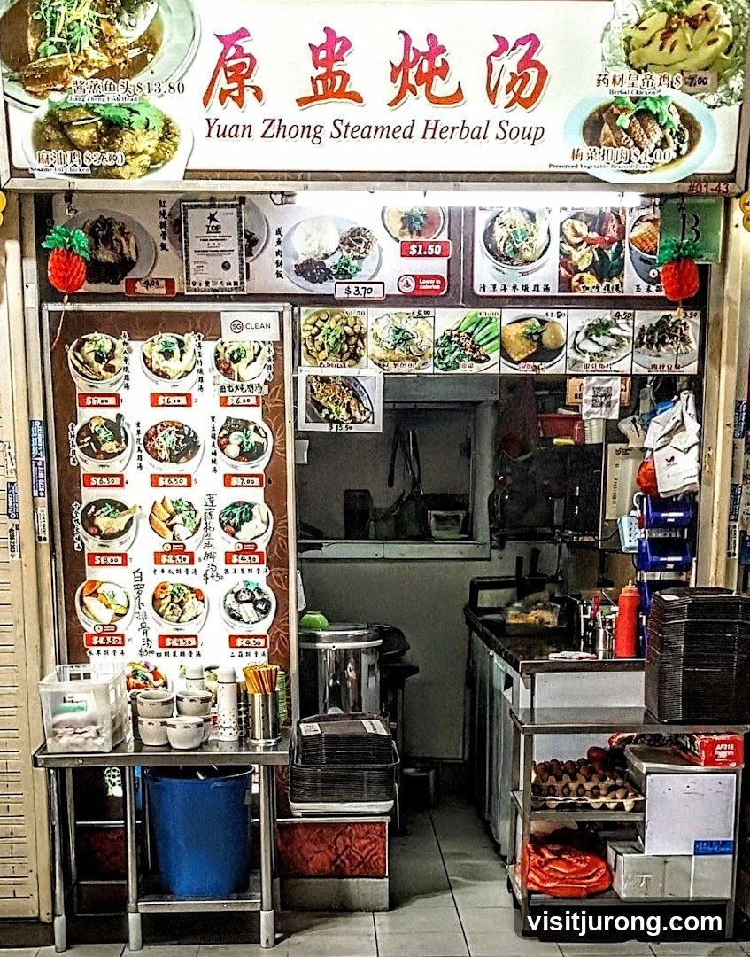 A food stall with a large menu board displaying various soups and dishes. The stall has a clean and organized appearance with food items and ingredients visible.